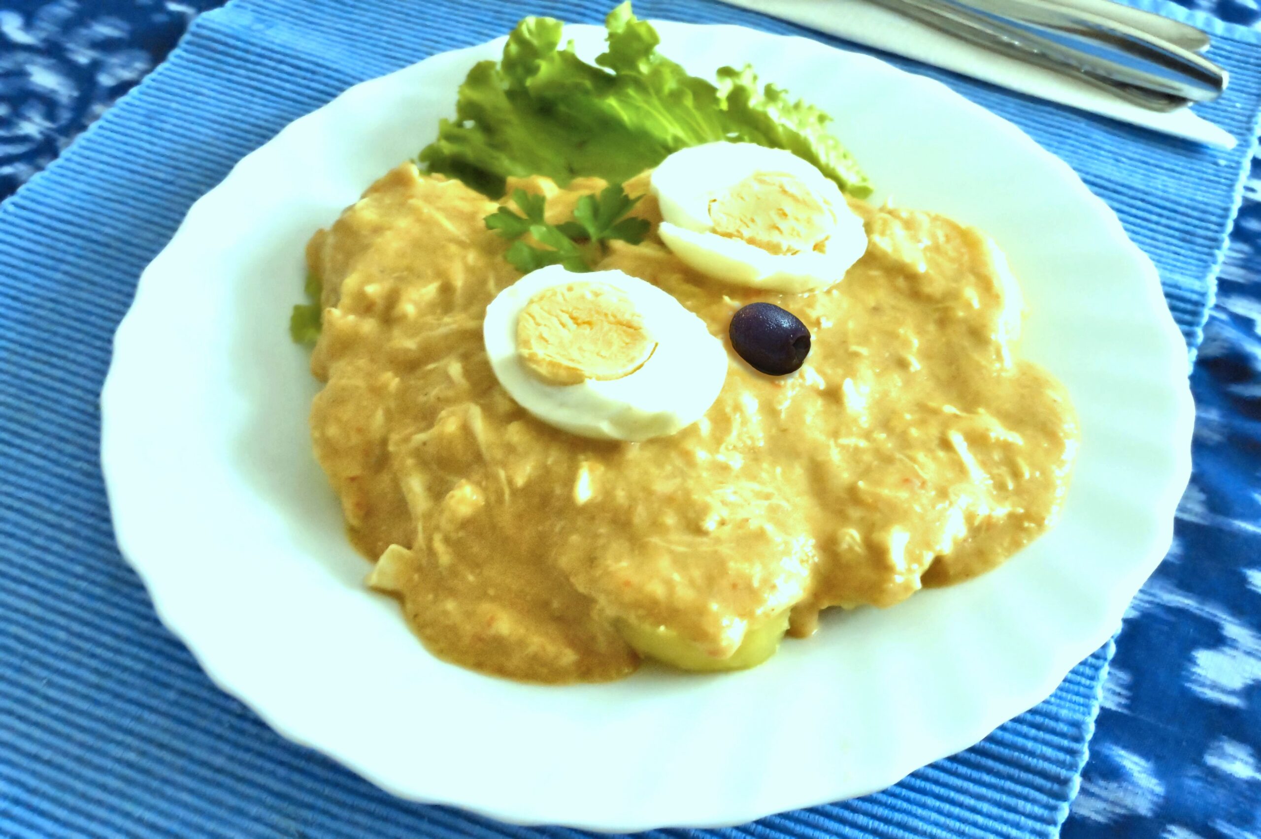 Ají de gallina peruano con salsa amarilla, papa, huevo y aceituna