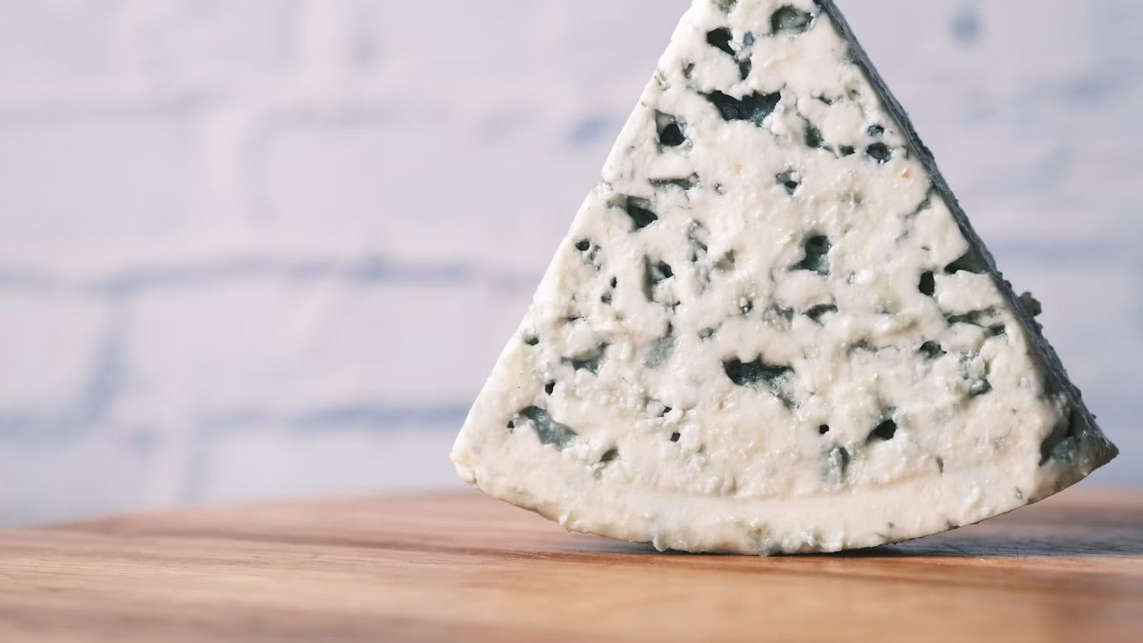 Cuña de queso azul con vetas oscuras sobre una mesa