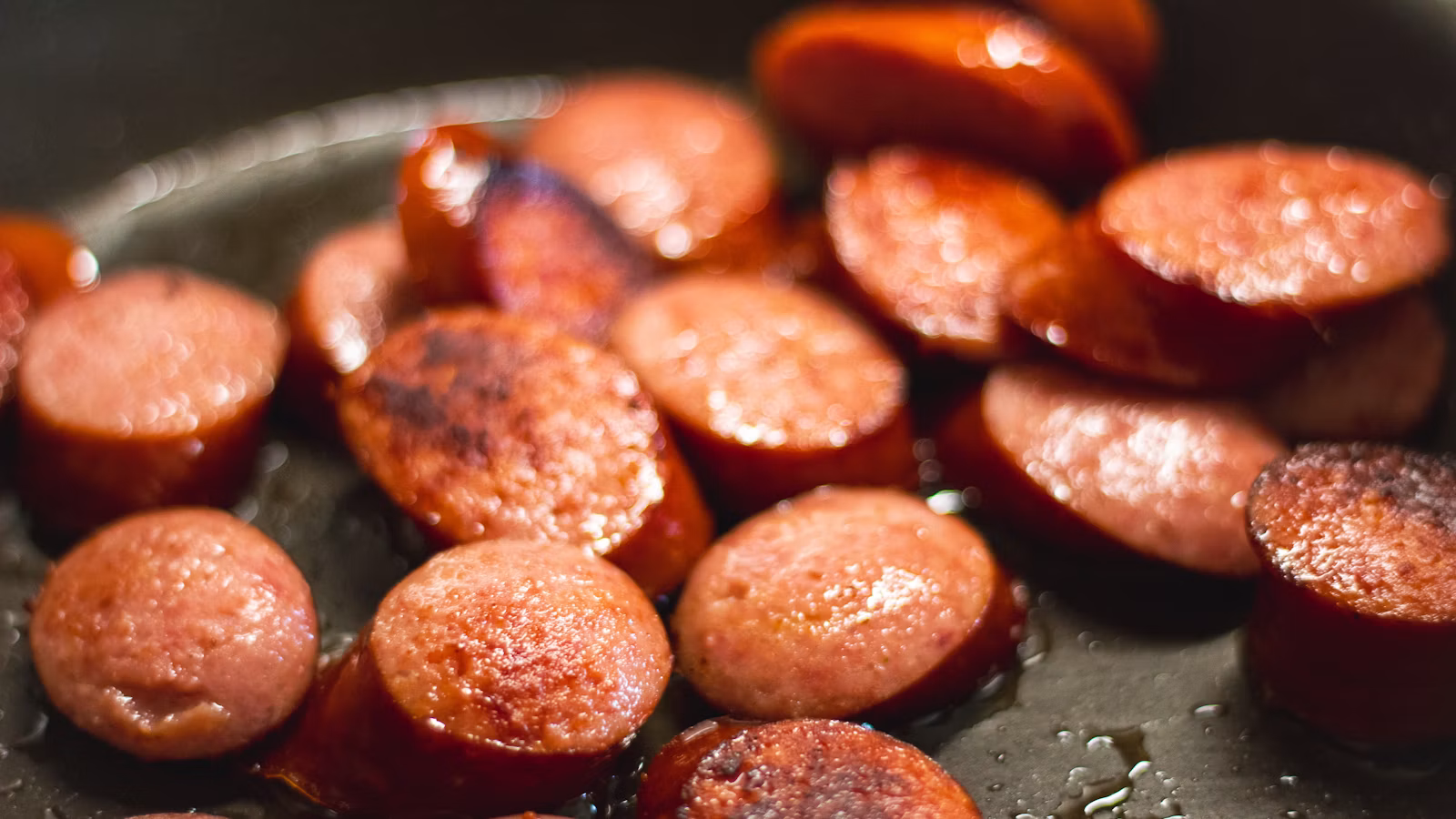 Embutidos cocinándose en una sartén
