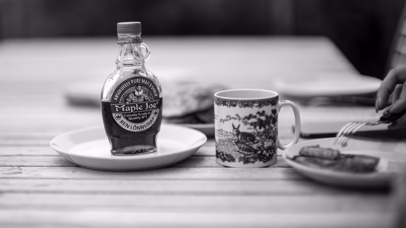 Botella de jarabe de arce puro o miel de maple junto a una taza
