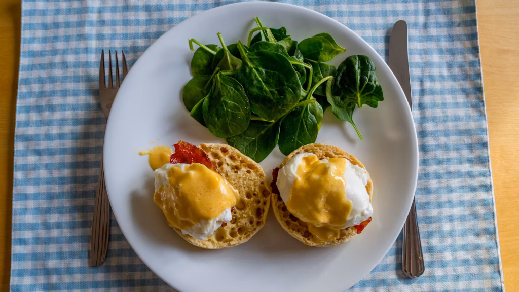 Dos huevos pochados con salsa amarilla sobre pan y jamón