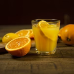 Jugo de naranja natural servido junto a naranjas frescas