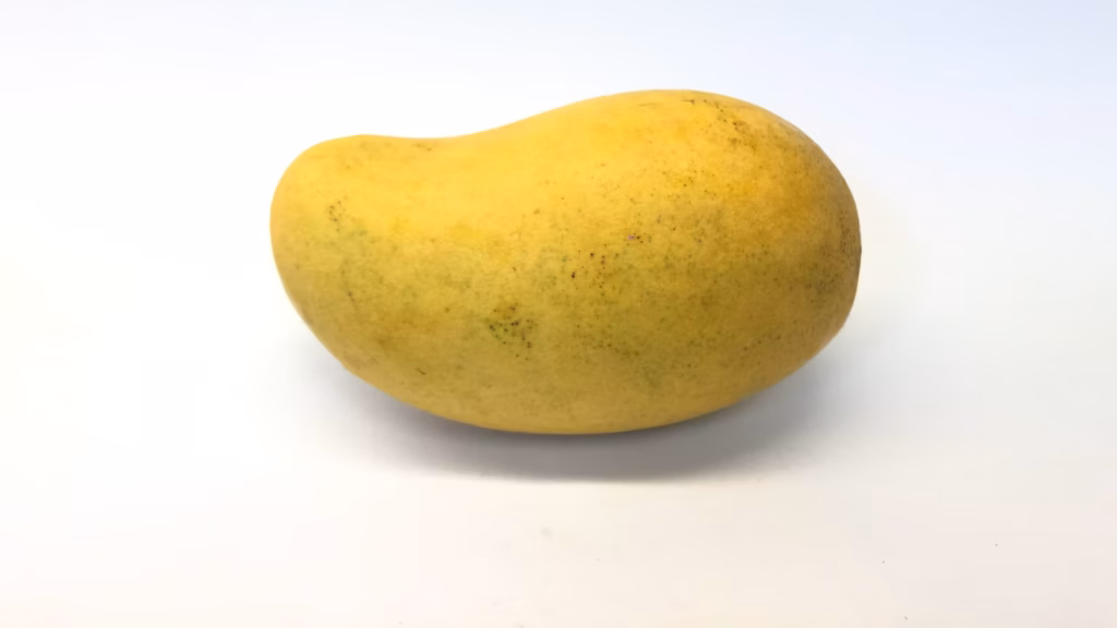Mango amarillo entero de forma alargada sobre fondo blanco