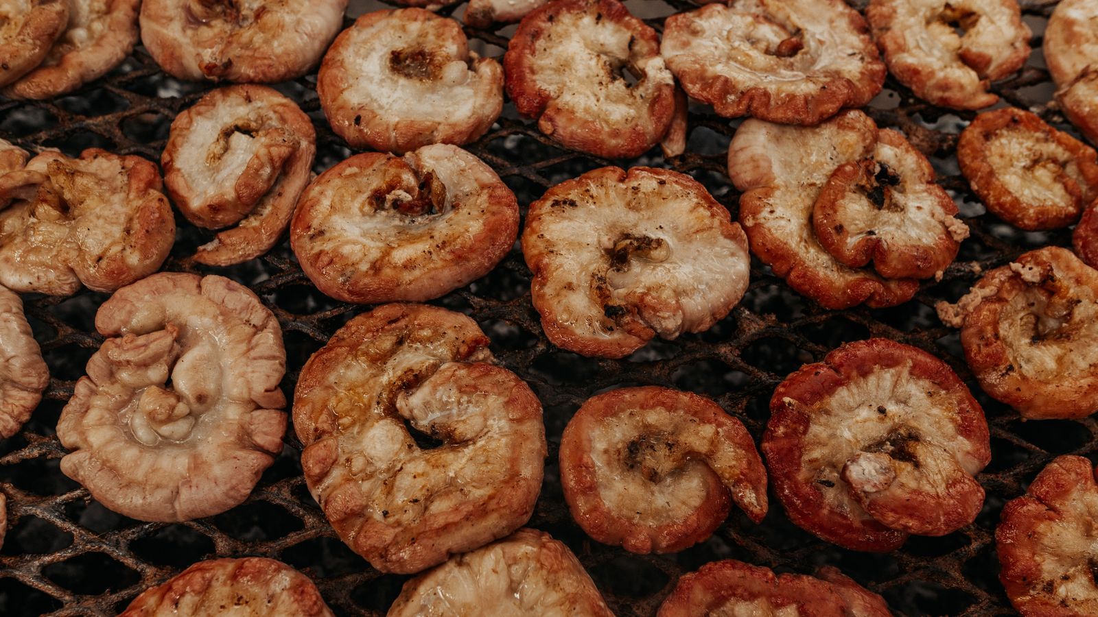 Detalle de mollejas de res dorándose sobre la parrilla