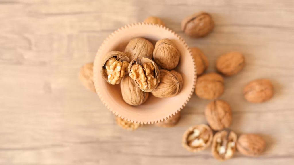 Nueces enteras y partidas en un cuenco sobre mesa de madera