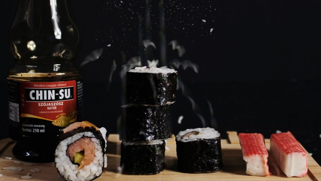 Palitos de surimi junto a rollos de sushi sobre una tabla