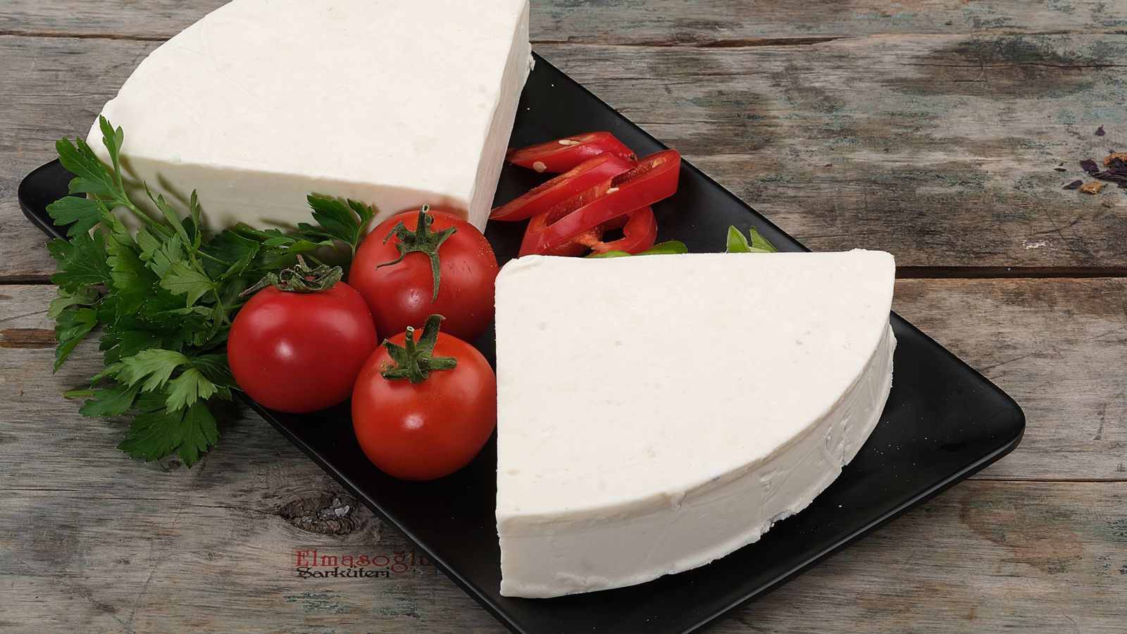 Porciones de queso blanco junto a tomate y hierbas