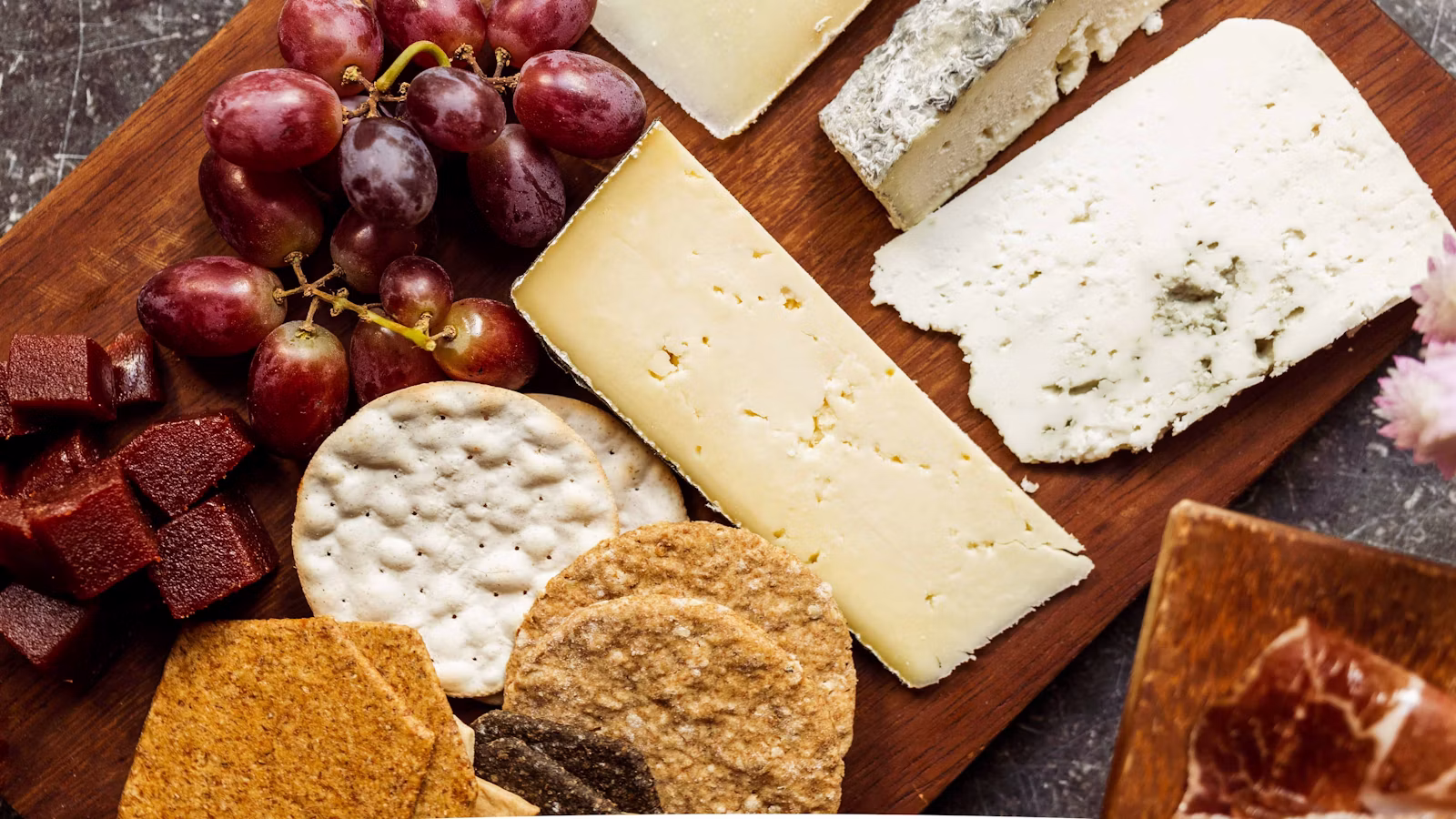 Tabla de quesos variados, incluido queso azul, con uvas y galletas