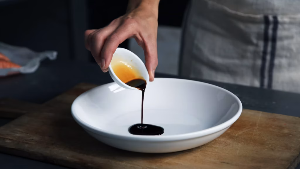 Líquido oscuro vertido desde un recipiente blanco a un plato