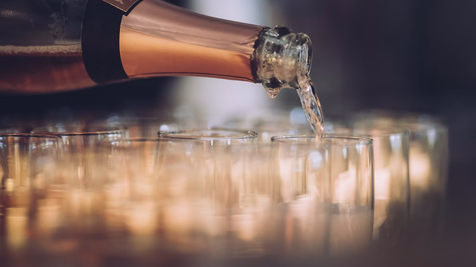 Botella sirviendo vino espumoso en copas de flauta