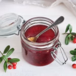 Salsa roja de fruta servida en un frasco con cuchara