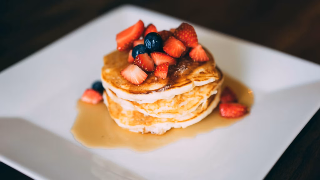 Hot cakes apilados con fresas y arándanos para servir