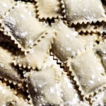 Ravioles caseros rellenos sobre una superficie enharinada