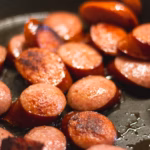 Salchichas doradas cocinándose en una sartén