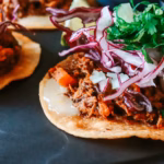 Tacos de barbacoa con carne de res deshebrada, cebolla y cilantro
